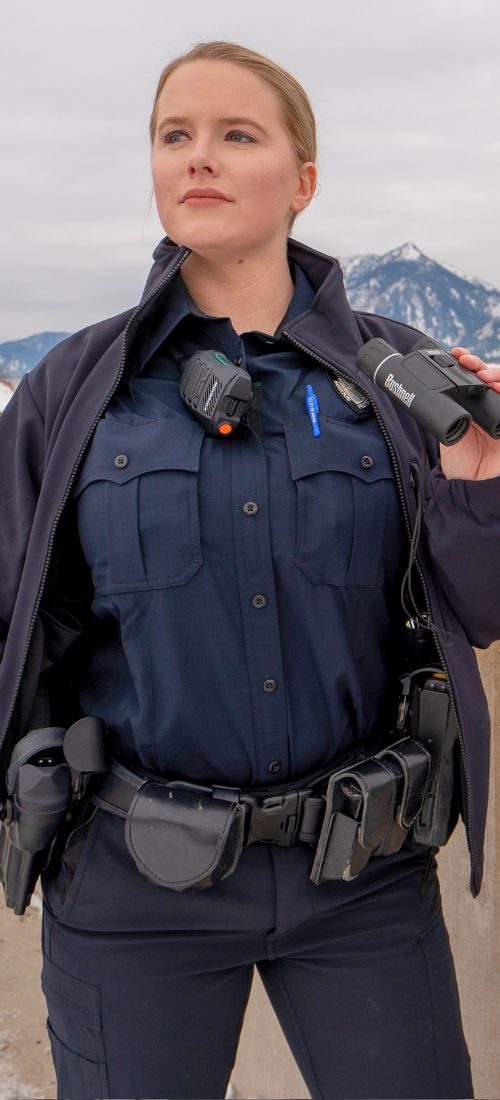Police officer wears class b women's uniform shirt overlooking Winter mountains