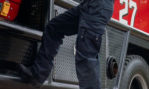 Firefighter shown wearing FlexRS EMT pants while climbing in to engine