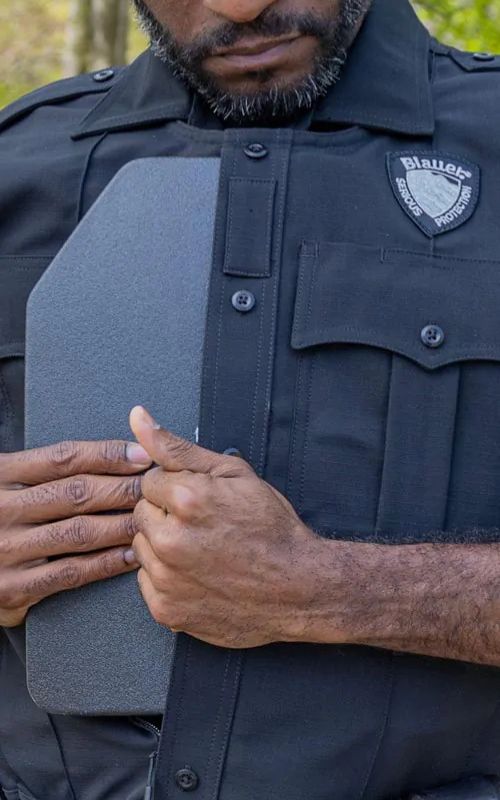 An officer slides an armor plate in to the front of his Armorskin Vest Carrier