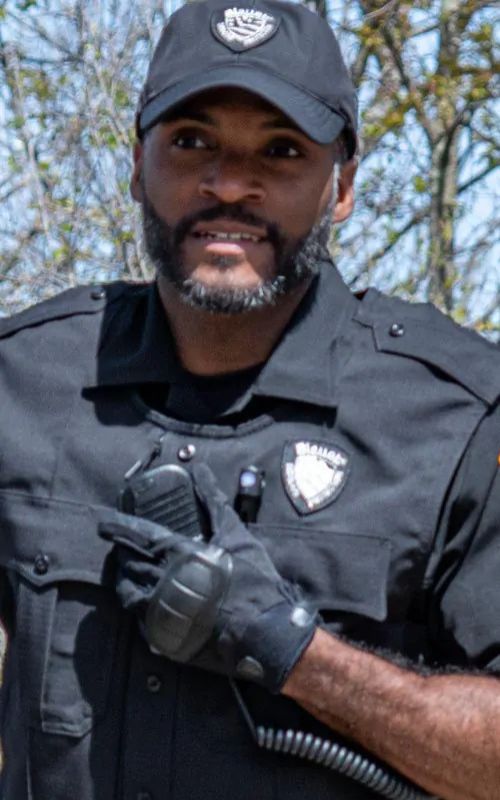 An officer wears a Navy Vest Carrier, matching short sleeve Navy Base Shirt, and hat and gloves for a cohesive, matching uniform look