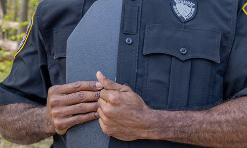 An officer slides an armor plate in to the front of his Armorskin Vest Carrier