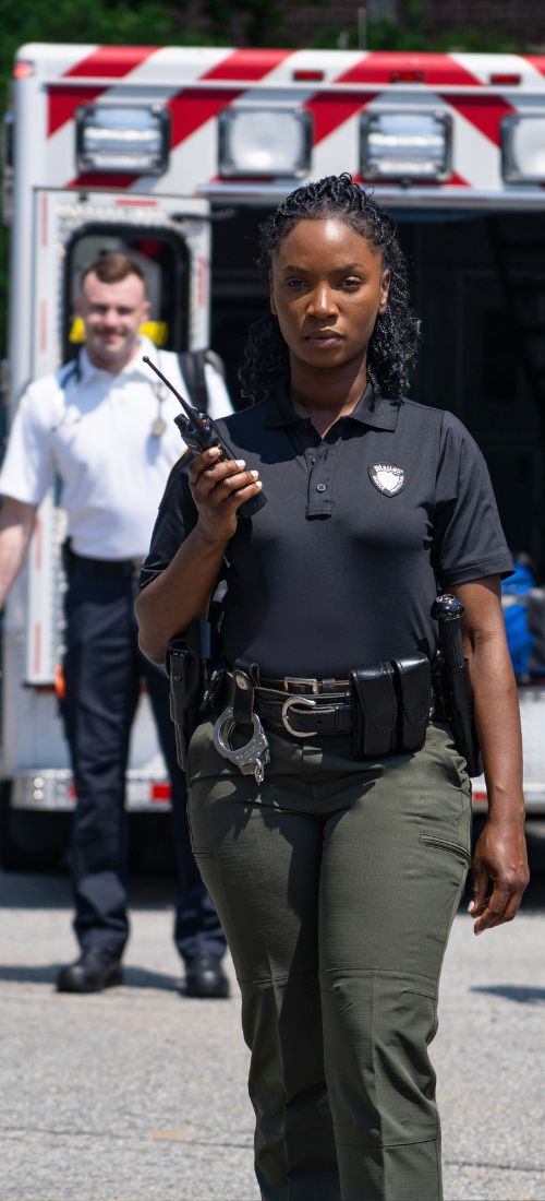 Female officer leads a team of responders in front of an ambulance and police car